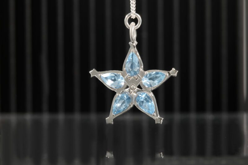 Sterling silver necklace in the shape of a star with five blue stones as the petals.